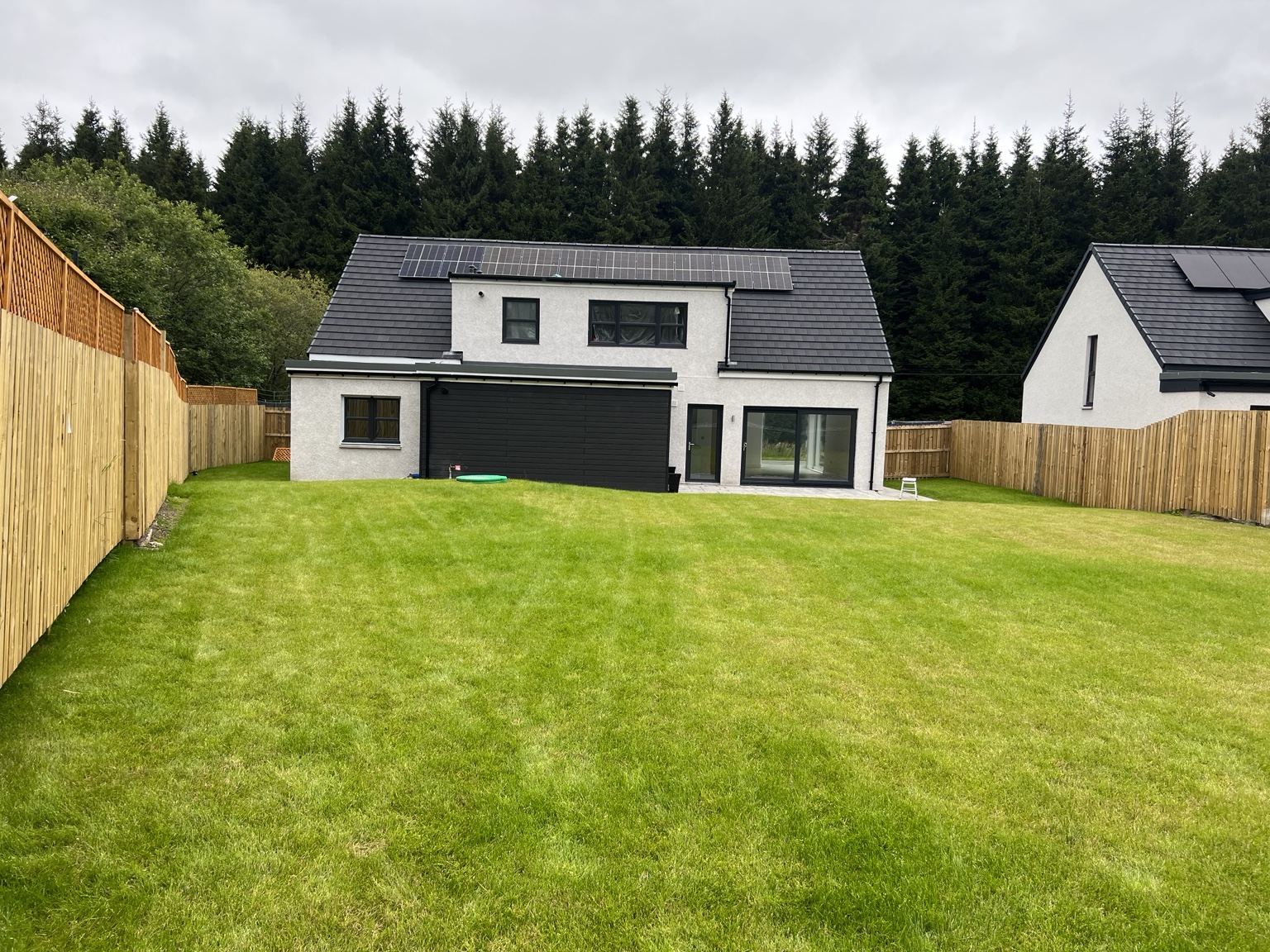 Completed two-storey rear elevation with solar panels and generous garden glazing